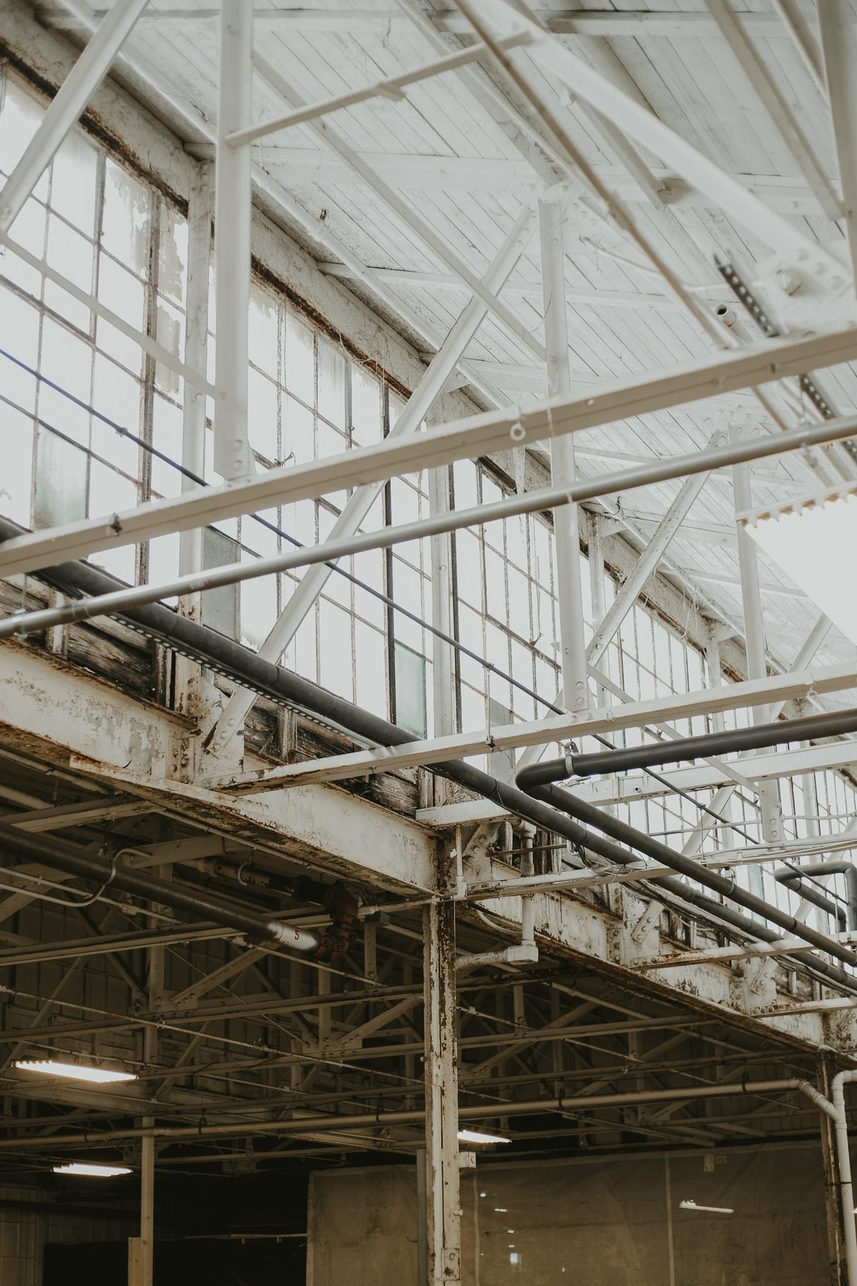 Interior of a tall white-painted industrial bay with steel trusses and rows of windows