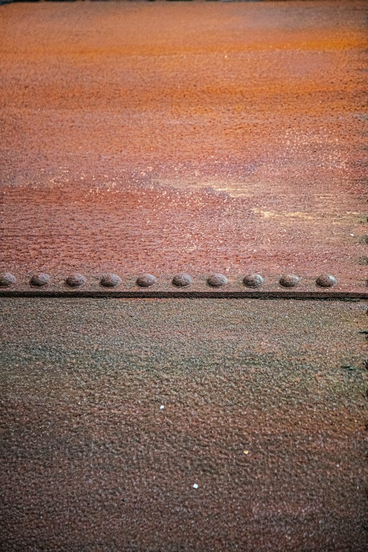 Weathered steel plate with a line of rivets across it